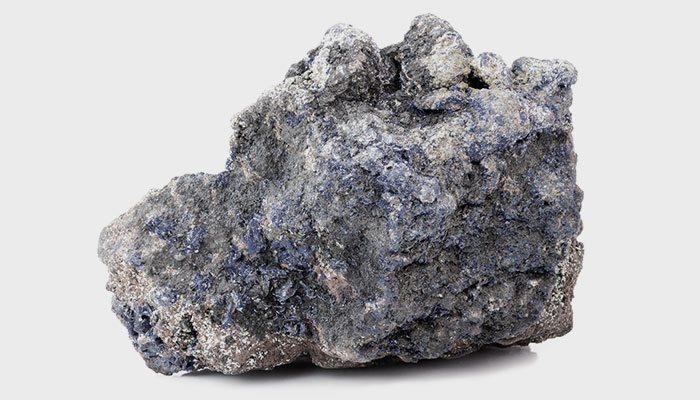 A raw chunk of cobalt ore on a white background.